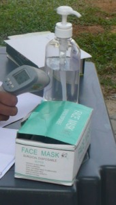 a hand sanitizer and a box of face mask are available at the scanning temperature table